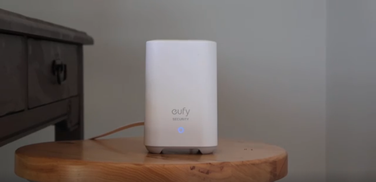 Eufy HomeBase 2 security hub placed on a wooden table beside a drawer unit