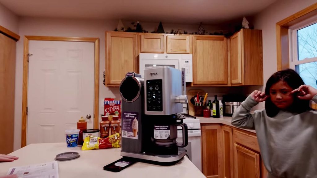 Ninja Creami Swirl on the kitchen counter while a kid covers her ears