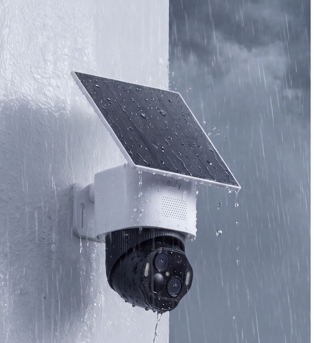 eufy SoloCam E50 wall-mounted outdoors in rain — dual-lens head and solar panel