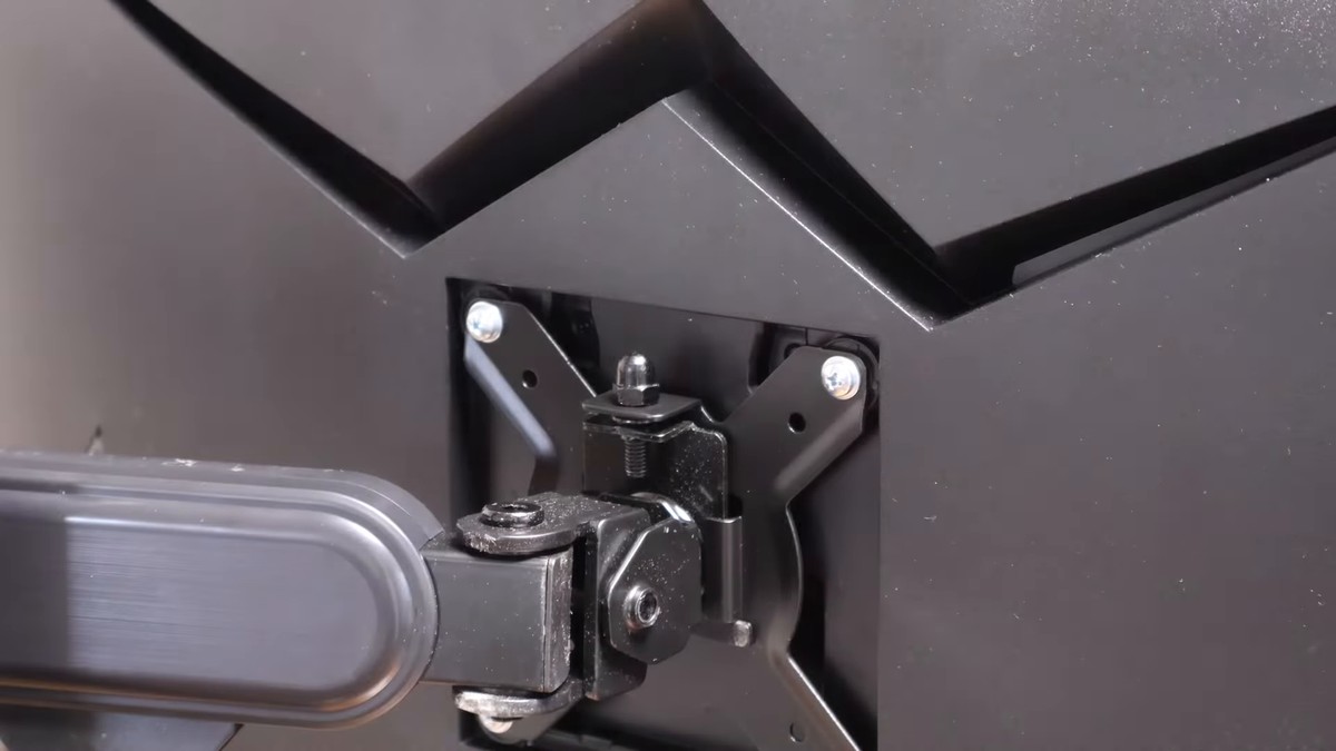 Close-up of an ELESTAND monitor arm joint bolted to the VESA bracket on the back of a monitor