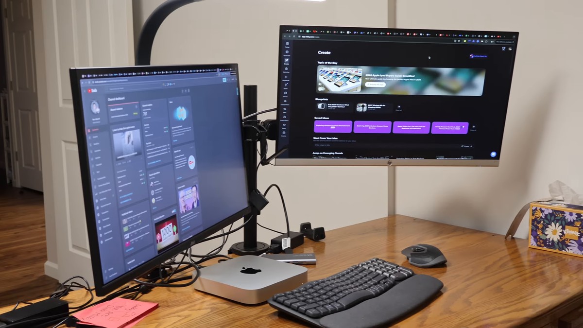 Two monitors raised on the ELESTAND dual mount above a tidy wooden desk with a keyboard, mouse, and Mac mini