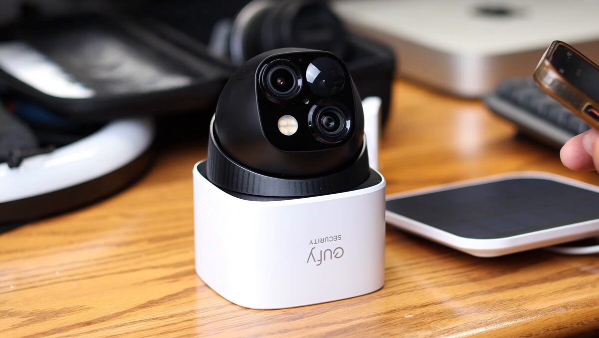 eufy SoloCam S340 on a desk showing its two camera lenses and spotlight, with its solar panel beside it