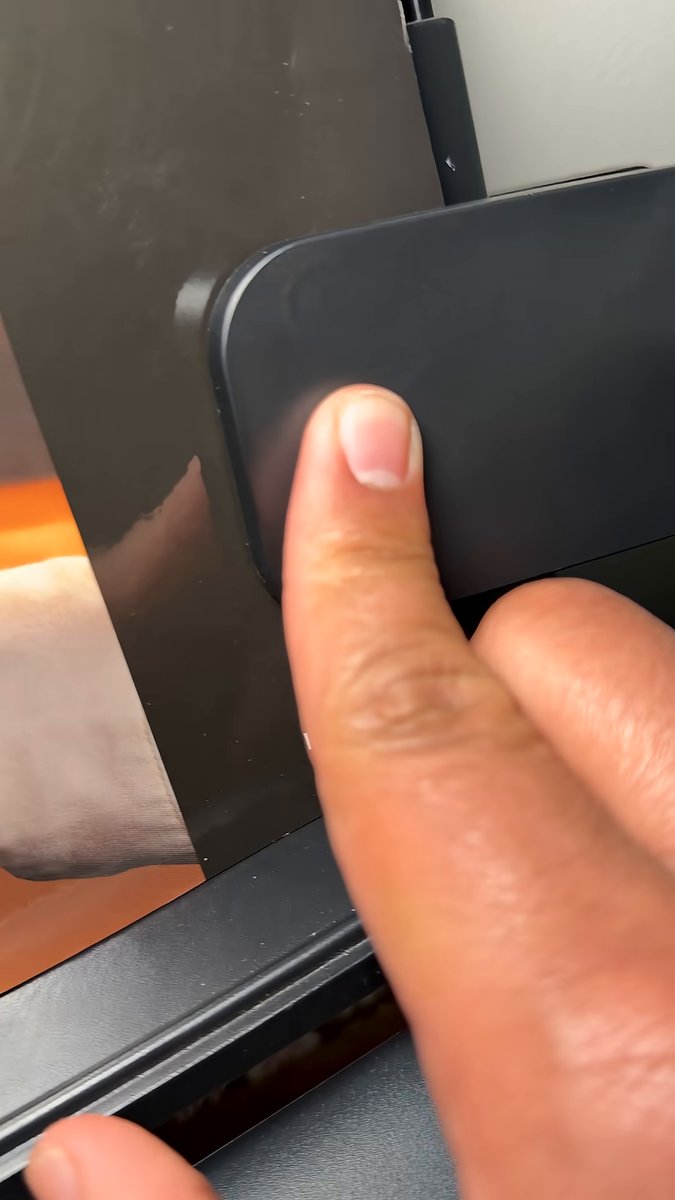 Finger holding the single button on the Honeywell clip-on lamp base to dim the light
